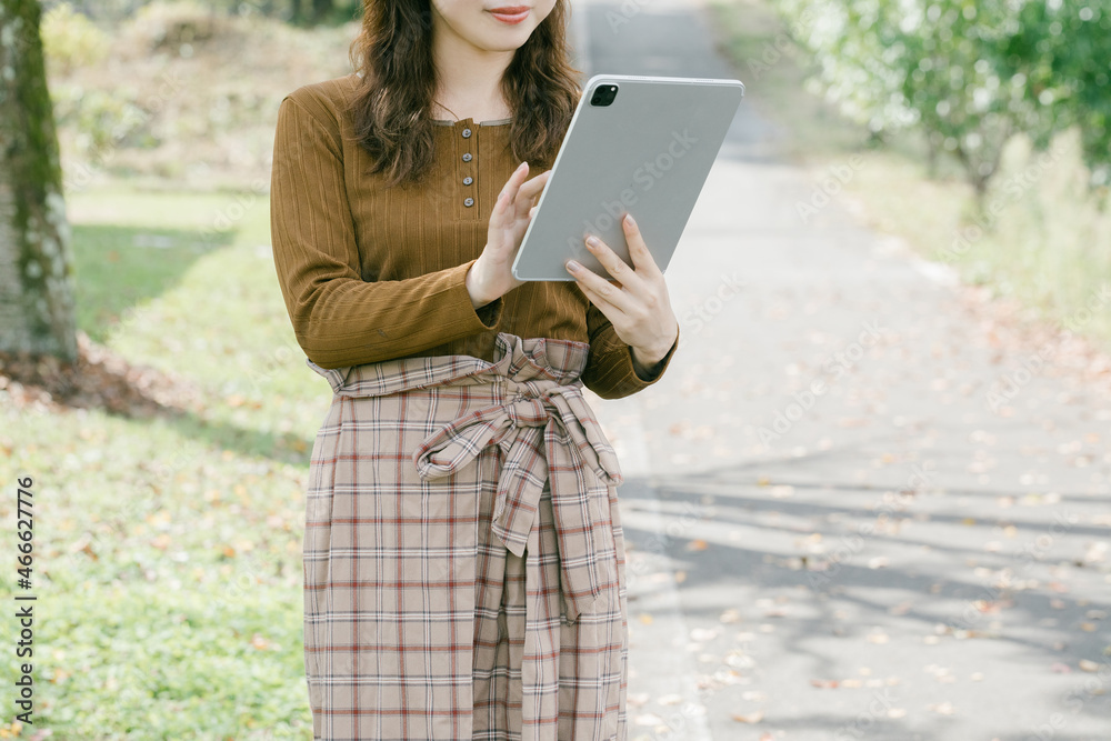 Poster タブレットを操作する女性　
屋外でタブレットを操作する女性