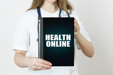 Fototapeta na wymiar The doctor is holding a tablet with the inscription - HEALTH ONLINE