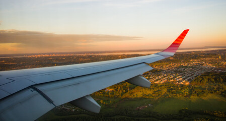 Viaje en Avión .Volando sobre la ciudad hacia el destino. Paisaje sobre las nubes. Ala de Avión