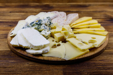 Cheese platter with different kinds of cheese on wooden table