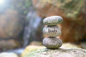 Stones stacked on top of each other. Text body mind soul on stone