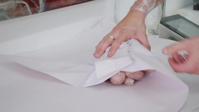 A butcher wrapping sausages in butchers paper. 