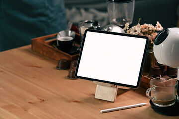Mock up digital tablet, coffee cup and coffee machine on wooden table.