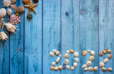 Seashells in the form of numbers 2022 on a background of boards. Summer vacation for the new year.
