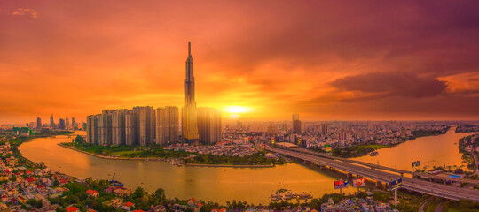 Aerial sunset view at Landmark 81 is a super tall skyscraper in center Ho Chi Minh City, Vietnam and Saigon bridge with development buildings, energy power infrastructure.