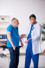 Fototapeta premium Old male patient visiting young male doctor