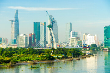 Fototapeta na wymiar Aerial view of center Ho Chi Minh City, Vietnam with Bitexco Financial tower, Thu Thiem 2 bridge, buildings, energy power infrastructure. View from the Saigon river.