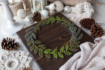 Christmas wreath, made on a wooden board with threads using string art technique, beautiful New...