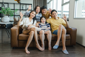 Portrait of happy Multi-generational Asian family in living room at home. Smiling parents, grandparents and happy children looking at camera. Portrait of extended family group sitting together