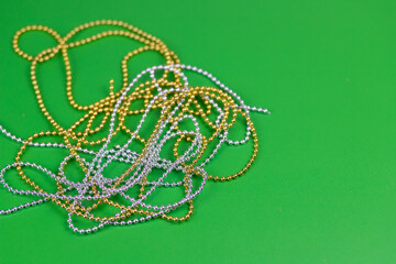 Christmas composition of gold and silver beads on a green background.