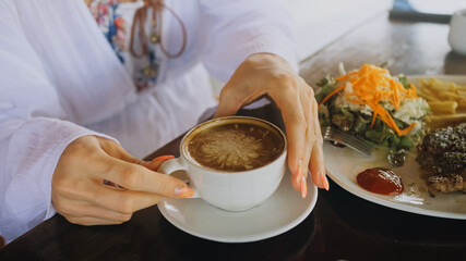 Woman drinking tasty beverages coffee Cappuccino Latte Art. Traveler spending time in traditional local floating cafe on water. Attractive blonde girl having breakfast outdoor. Tropical view