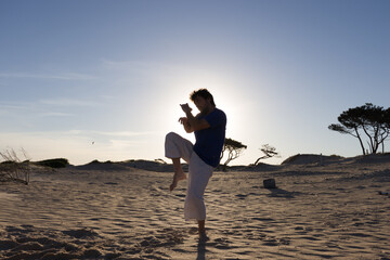 retroiluminación de un joven practicando artes marciales al atardecer