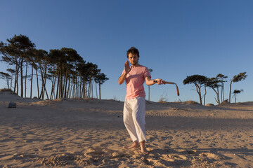 joven practicando artes marciales al atardecer sobre la arena con nunchakus 