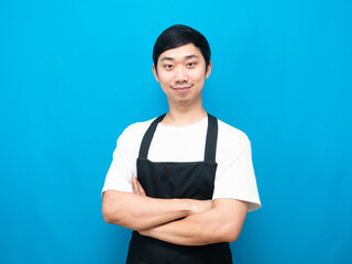 Man wearing black apron cross arm look confident blue background