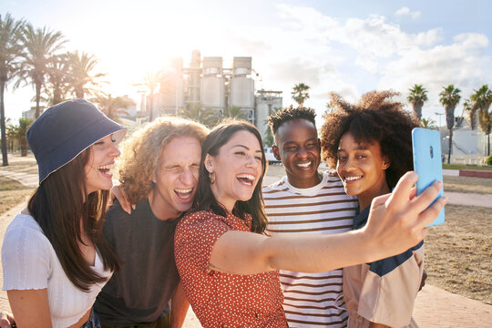 Group of urban youth enjoy taking a selfie in the city. They smile and have fun.