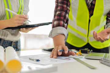 Two male and female engineers working on blueprints for the project worked with partners to create models and engineering tools in the house building concepts office.