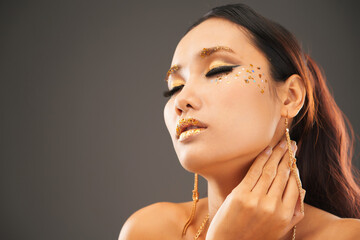 Attractive sensual young woman with golden make-up touching her neck and closing eyes