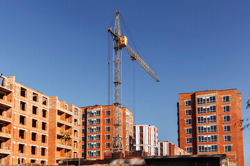 Construction site with new multistory houses and unfinished brick houses. Construction background, houses under construction, construction equipment, Multi-storey Brick Houses