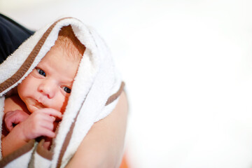 Mother holding her newborn baby daughter after birth on arms. Mum with baby girl, love. New born child cuddling in mama arms and looking at the camera. Bonding, family, new life.