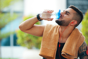 Thirsty sportsman drinking water after jogging outdoors in the morning
