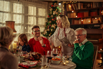 Joyful family celebrating Christmas at dining table.