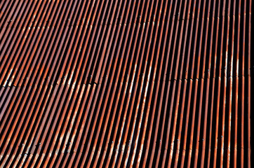 corrugated iron roof with a lightning conductor on top. the sheet is the whole rust and forms a texture similar to Manchester fabric. roof before renovation, blue sky