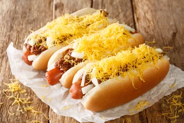 Foto op Canvas American chili hot dog with beef sausage, cheddar cheese and onions close-up on an old wooden background. horizontal © FomaA