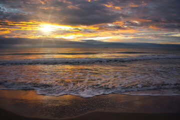 A beautiful and cloudy sunrise from the shore of a beach © vicenfoto