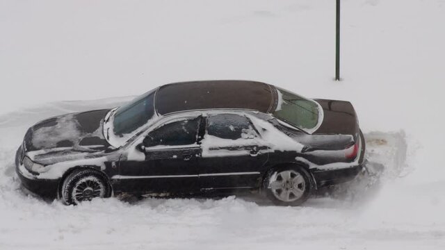 A passenger car slips in the snow in winter and tries to leave. Wheel slip on ice on winter tires. Blizzard, close-up