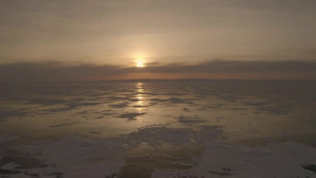 Winter landscape flight over frozen Lake Baikal, video filming at sunset