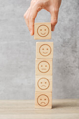 Man hand holding emotion face block. Customer choose Emoticon for user reviews. Service rating,...
