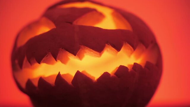 sinister Halloween pumpkin with burning candles inside, red background