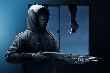 Criminal man in a hidden mask holding the shotgun while robbery the house