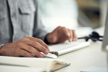Close-up of unrecognizable office worker using computer mouse and keyboard at workplace