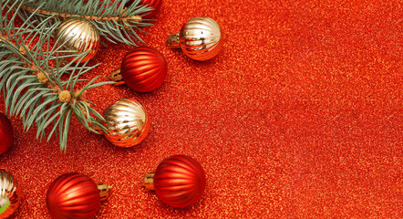 Obraz na płótnie Canvas Christmas decorative composition with fir branches, golden and red christmas balls on red shiny background. Christmas or New Year concept. Festive background with baubles and copy space.