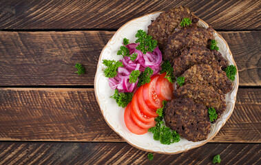 Chicken liver pancakes with vegetables  on wooden background. Fried chicken liver fritters idea. Rustic style. Top view