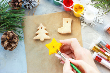 hand paints a star with yellow paint, toys for the new year with their own hands, creative decoration for a Christmas tree made of salt dough
