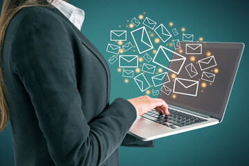 Close up of female hand using laptop with creative drawn email icons on blue background. Business, technology, communication and e-mail marketing concept.