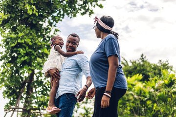 Portrait of enjoy happy love black family african american father and mother with little african girl child smiling and play having fun moments good time in summer park at home