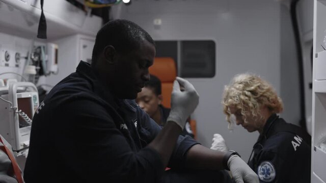African american paramedic crossing himself while riding in ambulance