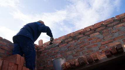 bricklayer lays bricks on scaffolding