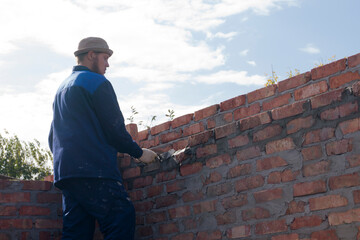 Obraz na płótnie Canvas bricklayer lays bricks on scaffolding