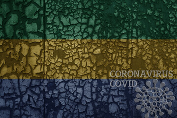 flag of gabon on a old metal rusty cracked wall with text coronavirus, covid, and virus picture.