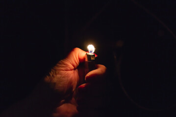 Woman hand holding a burning lighter in the dark black background.Closeup,selective focus.Copy space. - obrazy, fototapety, plakaty