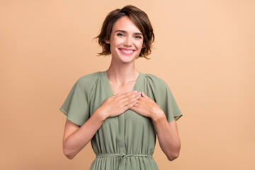 Photo of positive glad thankful lady hands chest beaming smile wear green dress isolated beige color background