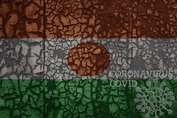 flag of niger on a old metal rusty cracked wall with text coronavirus, covid, and virus picture.