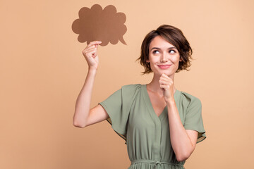 Photo of minded lady finger chin hold opinion cloud look empty space wear green dress isolated beige color background