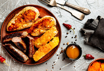 Fried chicken with sausages and white fish on plate