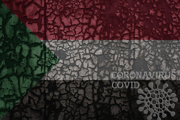 flag of sudan on a old metal rusty cracked wall with text coronavirus, covid, and virus picture.