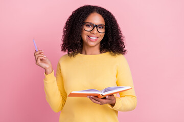 Photo of sweet clever dark skin girl dressed yellow pullover glasses writing book smiling isolated...